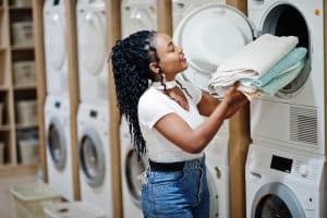 Woman placing folded laundry into a dryer at a self-service laundromat