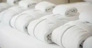 Clean white bathrobes folded neatly on a bed.